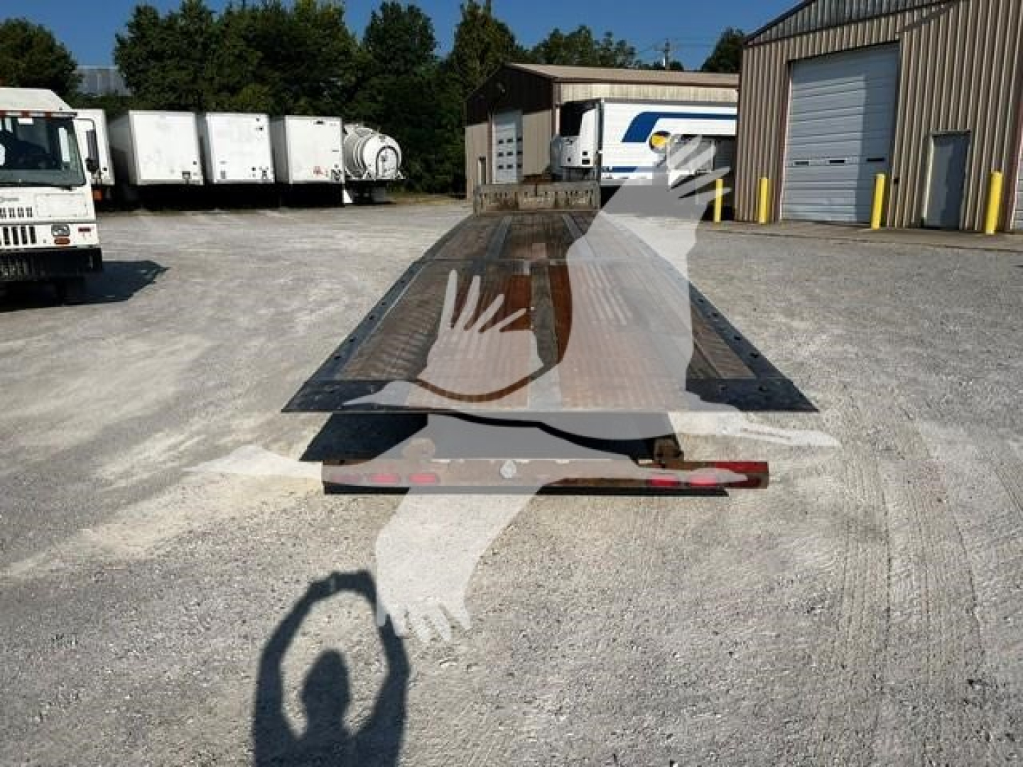 Industrial trailer deck with Landoll logo watermark, flatbed car carrier style, showing a long metal platform with hinge sections and a ramp in a service yard.