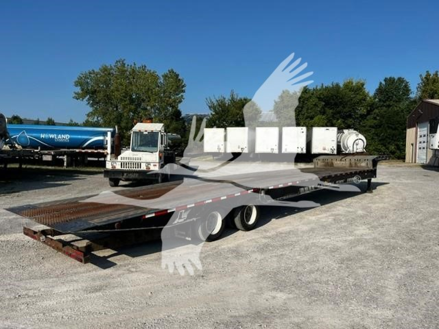 Landoll 93051-15 trailer with flatbed platform in an outdoor lot; logos and equipment visible including white cab truck, cylindrical tanks, and multiple white boxes in background.