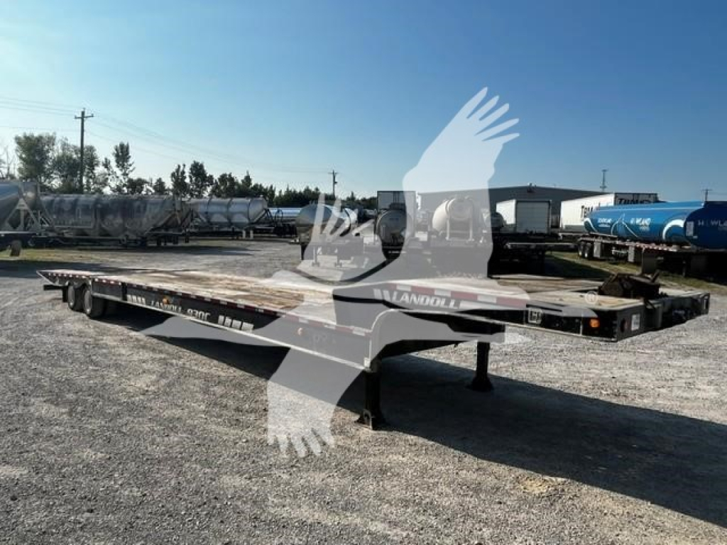 Trailer axle device showing Landoll 2011 model flatbed trailer with low deck, dual axles, and landing gear in an outdoor lot.