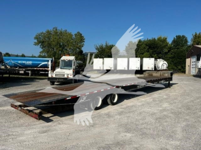 Landoll 93051-15 trailer with flatbed platform in an outdoor lot; logos and equipment visible including white cab truck, cylindrical tanks, and multiple white boxes in background.