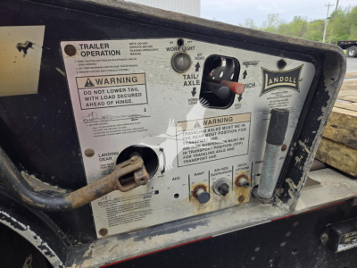 Trailer control panel with labels: WARNING DO NOT LOAD TAIL WITH LATCH AHEAD OF HINGE, TRAILER OPERATION text, and Randoll/landoll branding; various knobs, levers, and warning stickers visible.