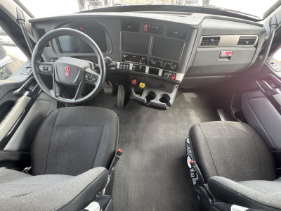 Kenworth T680 dashboard and two front seats interior view with steering wheel, center console, and control panels.