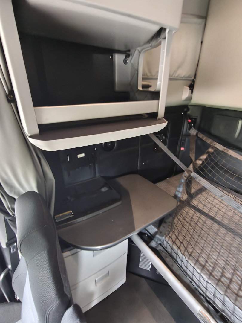 Kenworth T680 cab interior showing sleeper area with bunk bed and storage compartments.