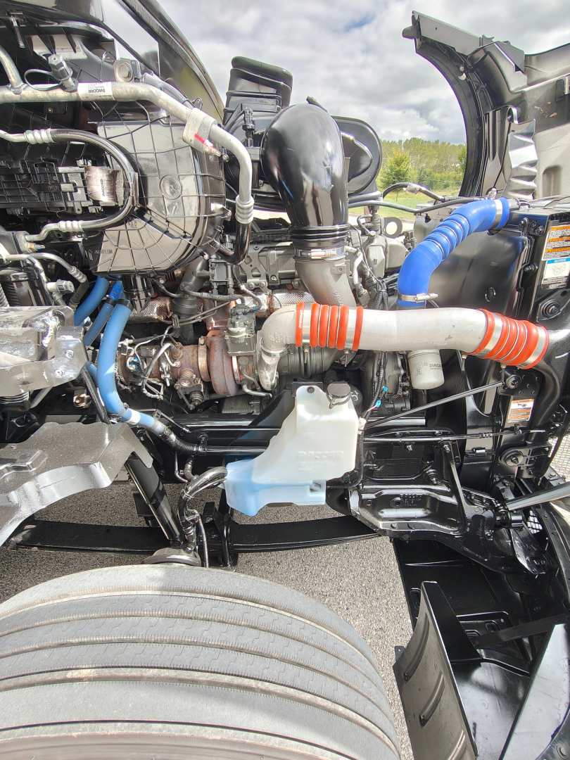 Kenworth T680 engine bay showing coolant reservoir, intercooler hoses, and various fluid lines.