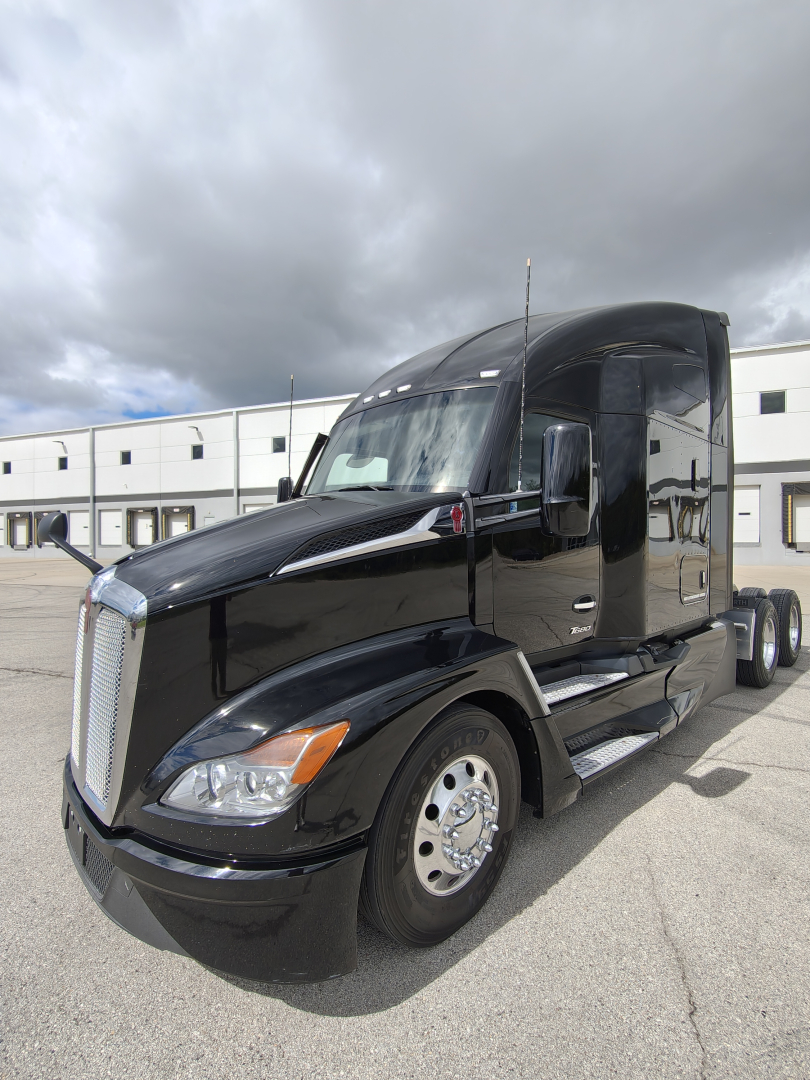 Kenworth T680 semi-truck in black paint with sleeper cab, front three-quarter view; chrome grille; headlights; side mirrors; wheel rims; no visible branding text legible on side.