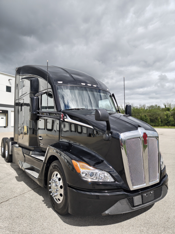Kenworth T680 tractor-trailer in black paint with chrome grille and dual headlights, front-left view.