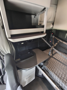 Kenworth T680 cab interior showing sleeper area with bunk bed and storage compartments.