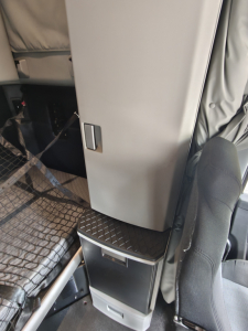 Kenworth T680 cab interior showing sleeper area with side storage drawers and step, interior paneling visible.