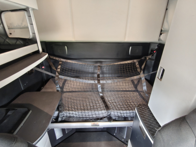 Kenworth T680 sleeper cab interior showing rear bunk area with net cargo organizer and shelves.