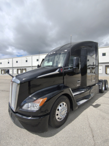 Kenworth T680 semi-truck in black paint with sleeper cab, front three-quarter view; chrome grille; headlights; side mirrors; wheel rims; no visible branding text legible on side.