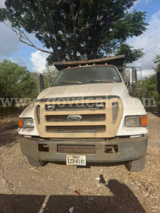 Front view of a beige 2005 Ford F-750 cab with Texas license plate, large grille, and utility bed in a yard.