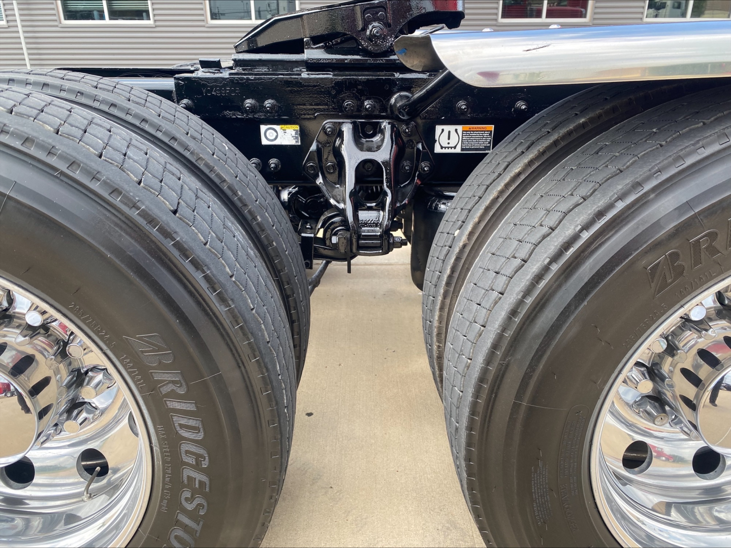 Peterbilt truck chassis and dual rear axles with Bridgestone tires, suspension hitch components visible between wheels.