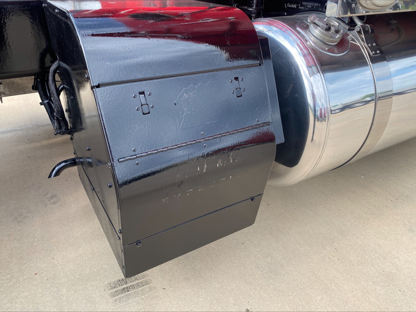 Peterbilt 389 truck exhaust/air intake area with black toolbox mounted near the chassis and chrome tank behind it.