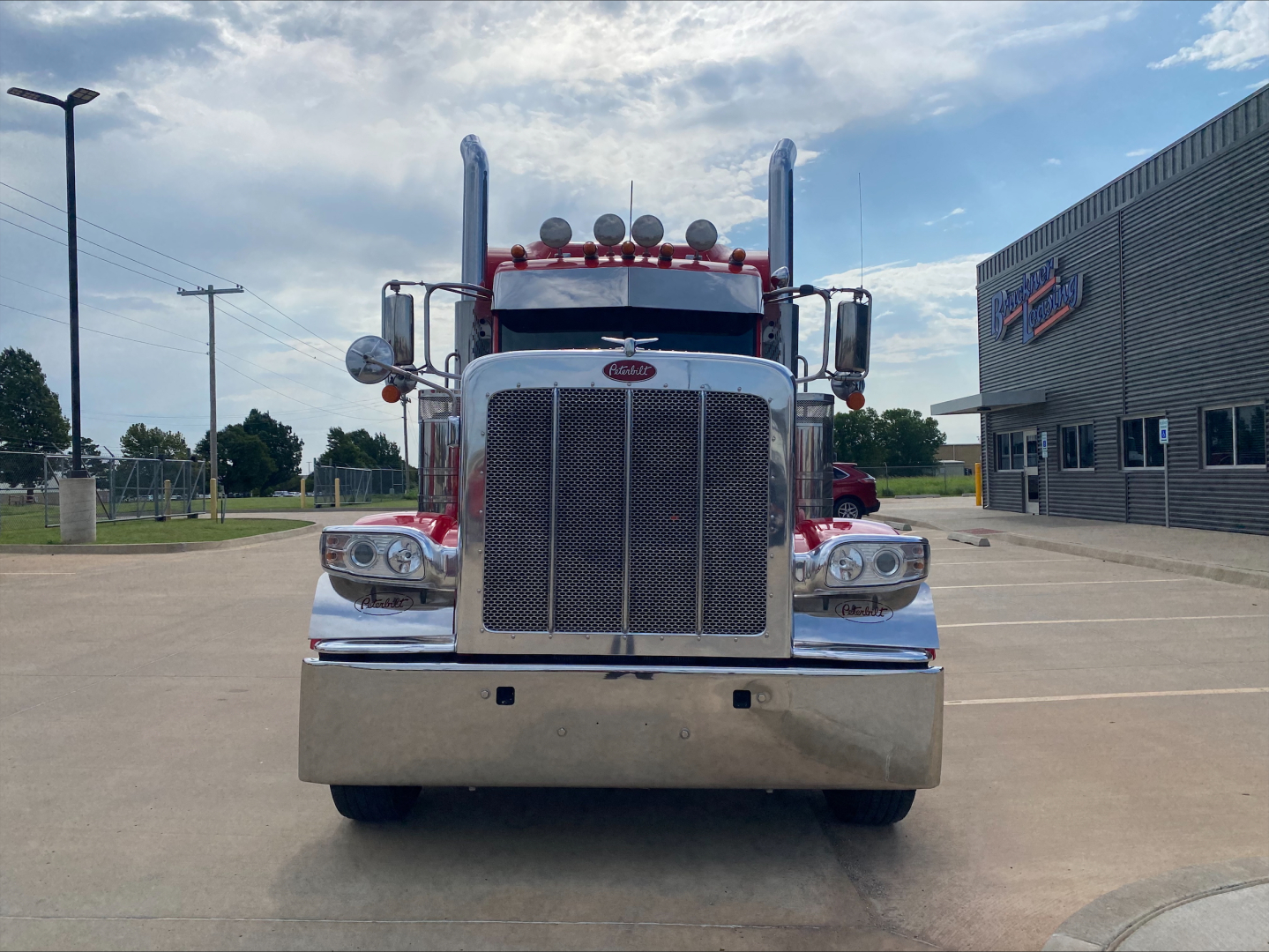 Peterbilt 389 front view showing large chrome grille, dual vertical exhaust stacks, and prominent bumper. Text on the grille reads Peterbilt emblem; no other legible labels visible.