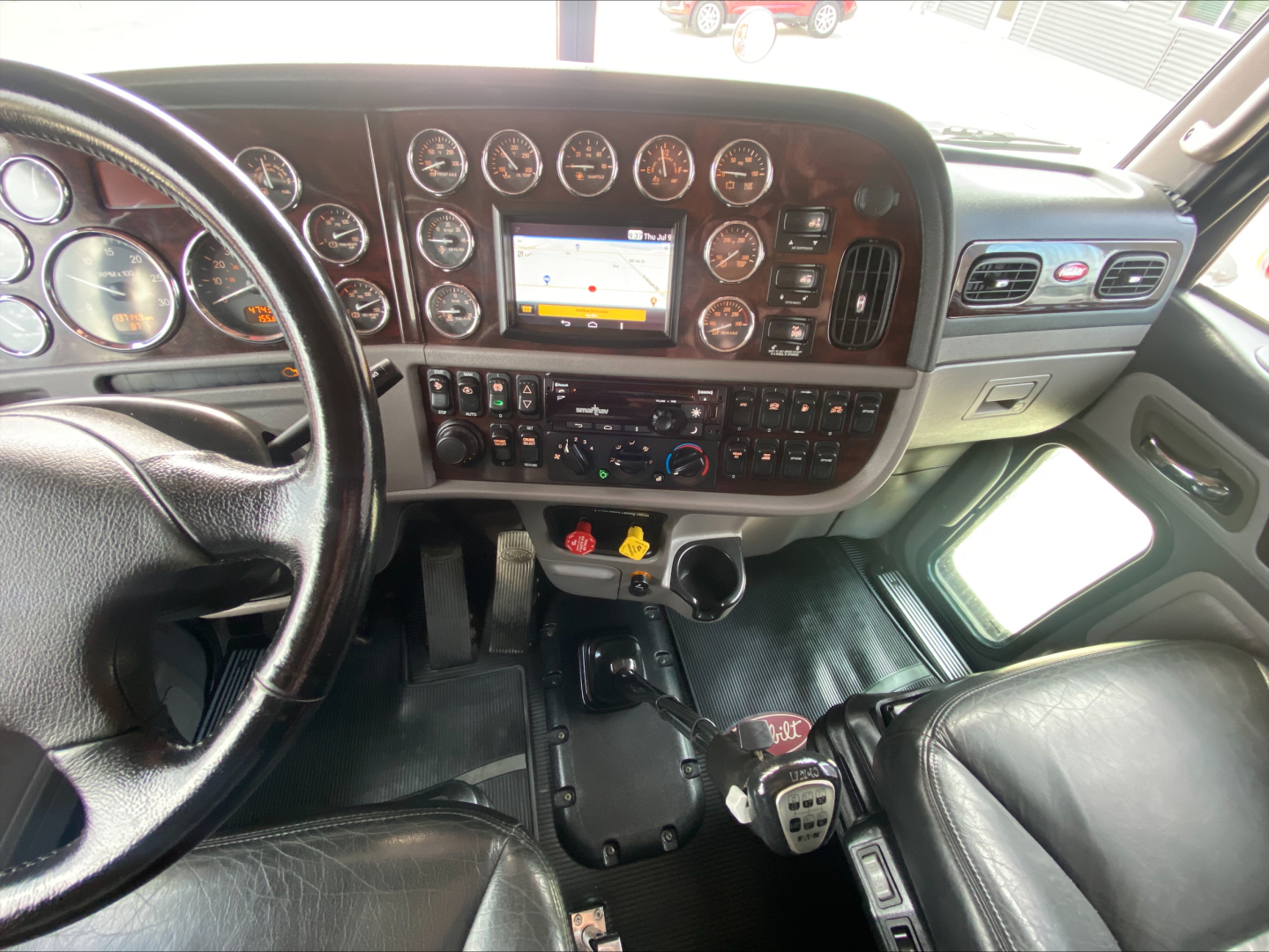 Peterbilt 389 cab interior showing instrument cluster and center console with gauges, touchscreen, and control panels.