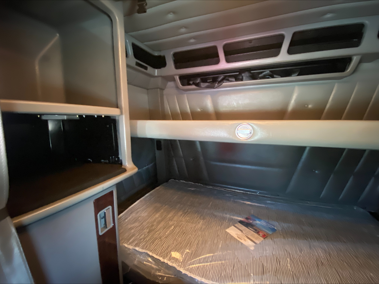 Peterbilt 389 sleeper cab interior/truck cabin storage bunker area with overhead vent slots and bed platform, 2021 model year showroom photo.