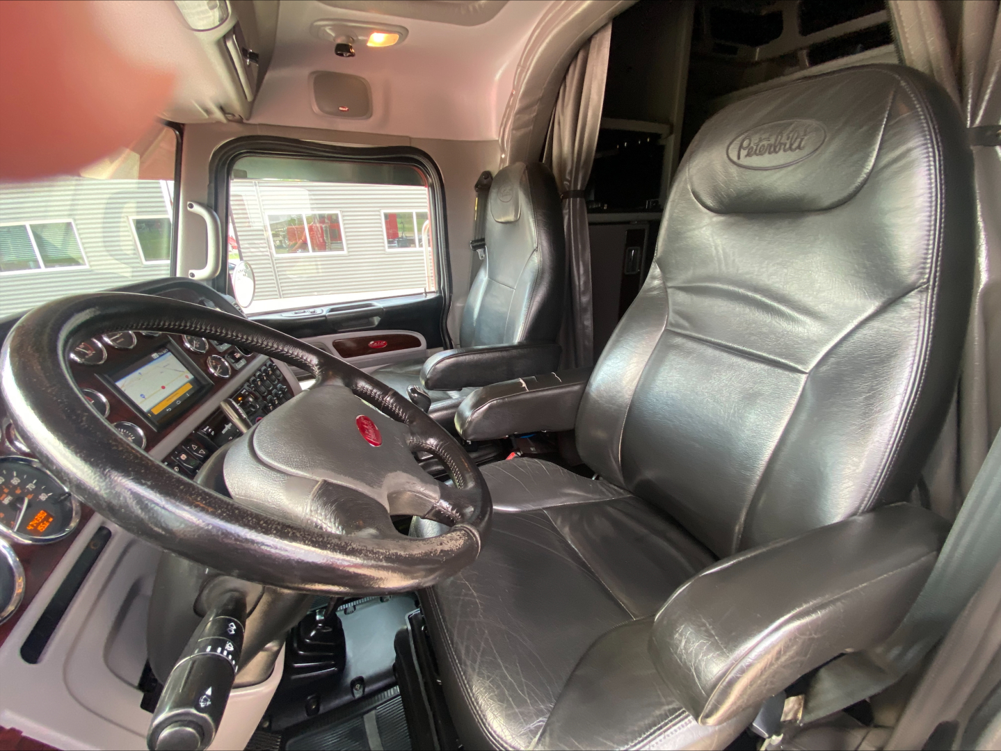 Peterbilt 389 truck interior showing steering wheel, captain seats, and dashboard with controls.