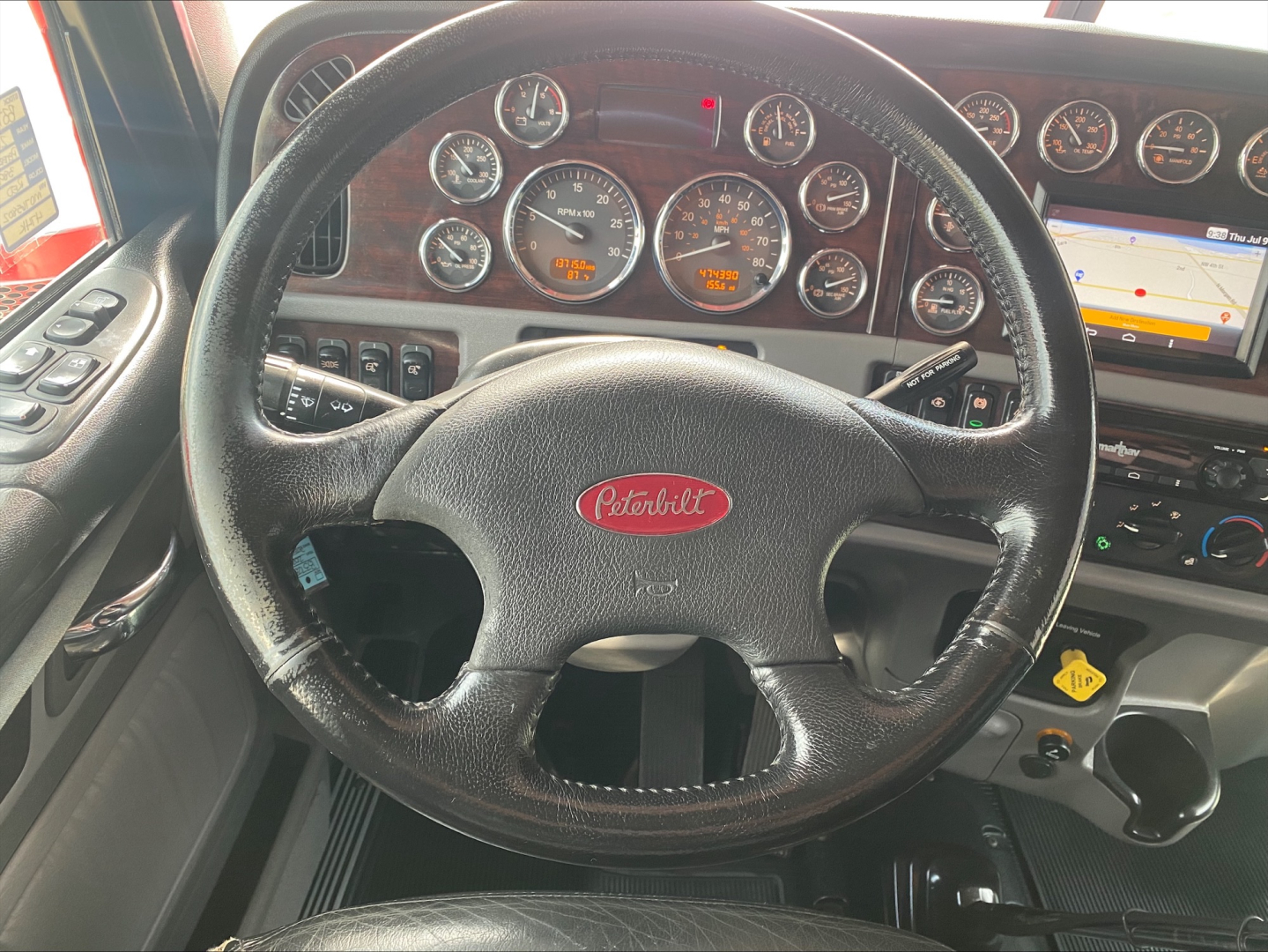 Peterbilt steering wheel and dashboard with multiple gauges in cab interior.