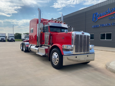Peterbilt 389 conventional sleeper truck in red with chrome bumper, shown from front-left angle in lot.