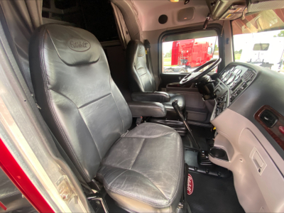 Peterbilt 389 truck interior showing driver and passenger seats, dashboard, steering wheel, and center console.