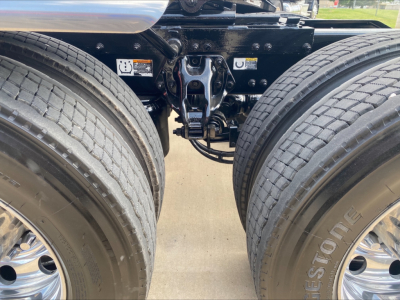 Peterbilt truck rear view showing dual rear axles with Bridgestone tires and suspension components; visible labels and hardware on frame.