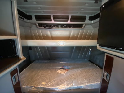 Peterbilt 389 sleeper cab interior cargo area showing captain’s bed with protective covering and overhead cabinets.