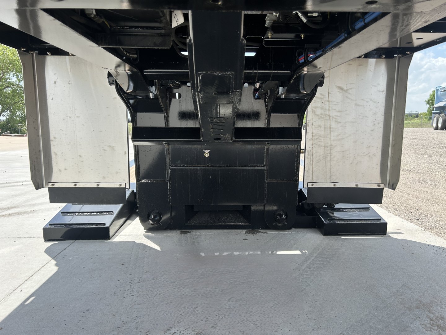 Front view of Alpha A70HDGC-M lowboy trailer undercarriage showing hydraulic detach system and dual drop-mounts with black steel frame and support blocks.