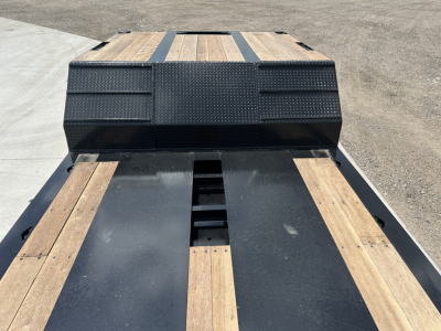 Flatbed trailer deck with wooden planks and metal frame; black tool/storage box at the front with textured paneling; no visible labels in the image.