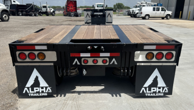Trailer rear view showing Alpha Trailers mud flaps, taillights, and wooden deck with black steel frame on a lowboy trailer.
