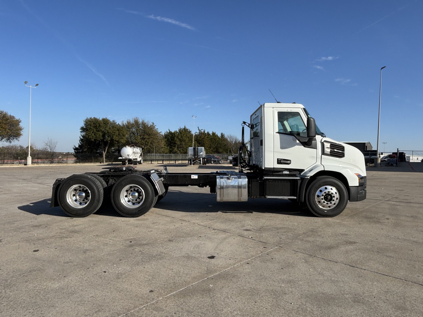 Truck chassis and cab in a parking lot showing Mack AN64T daycab configuration and wheel layout.