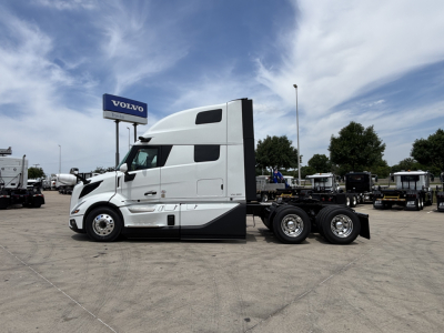 Volvo VNL64T860 truck tractor in a lot, side view, white cab with sleeper, no trailer attached.