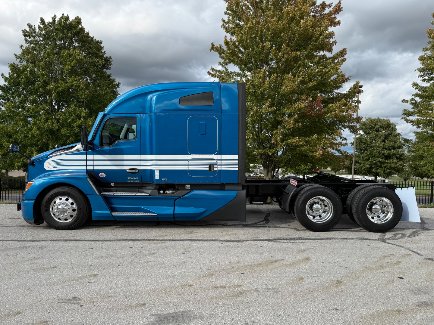 Kenworth T680 truck cab profile in blue with white stripe, side view showing sleeper cab and rear axles.