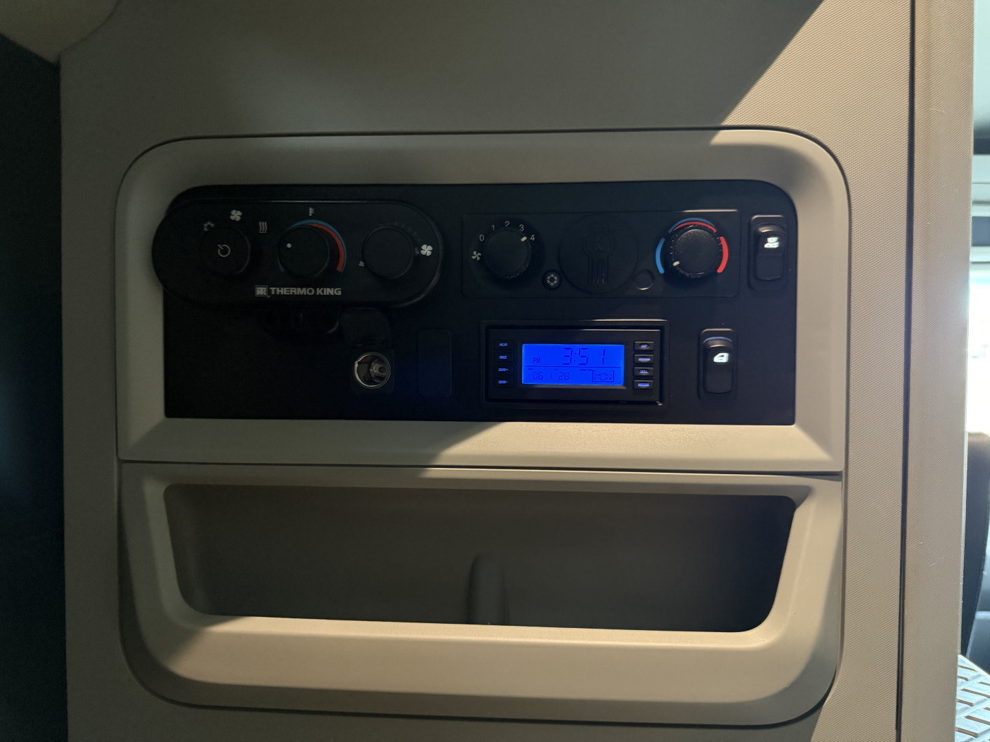 Kenworth T680 dash panel showing climate controls, stereo/display, and storage pocket.