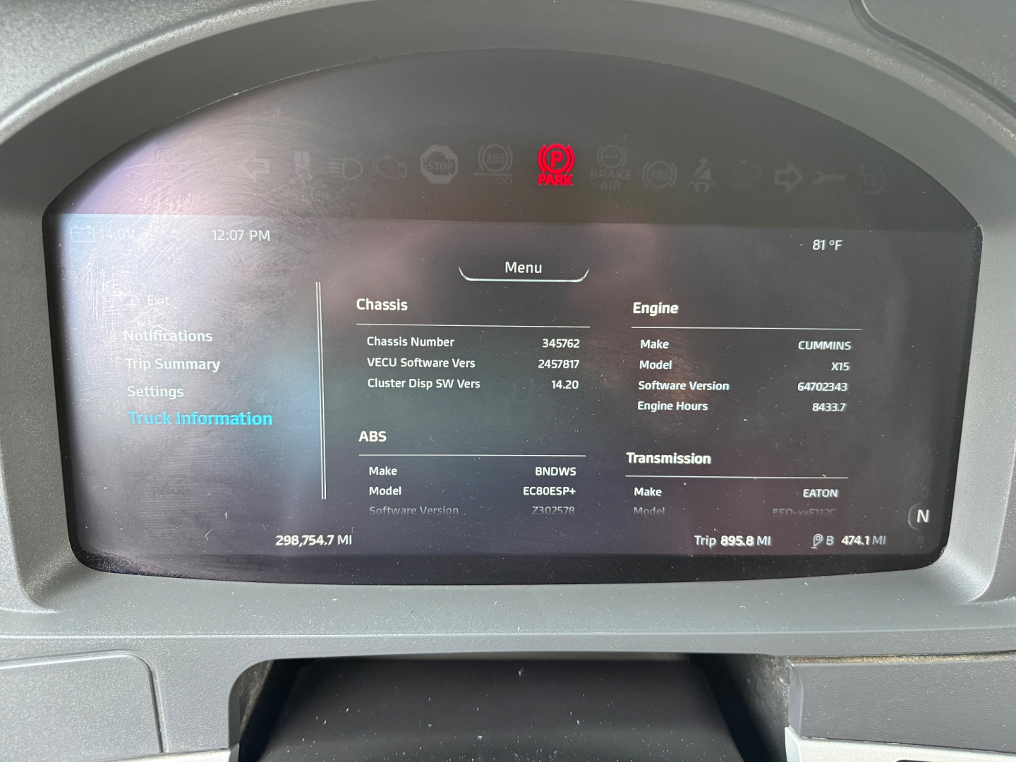 Dashboard display showing truck information: Chassis number, engine make/model, software version, and trip data in a Kenworth T680 cab interior.