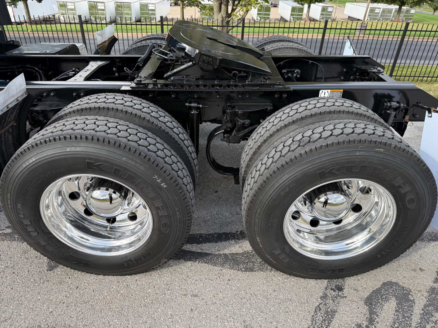 Kenworth T680 chassis rear view showing dual rear axles with large dual tires and chrome wheels, undercarriage components visible.