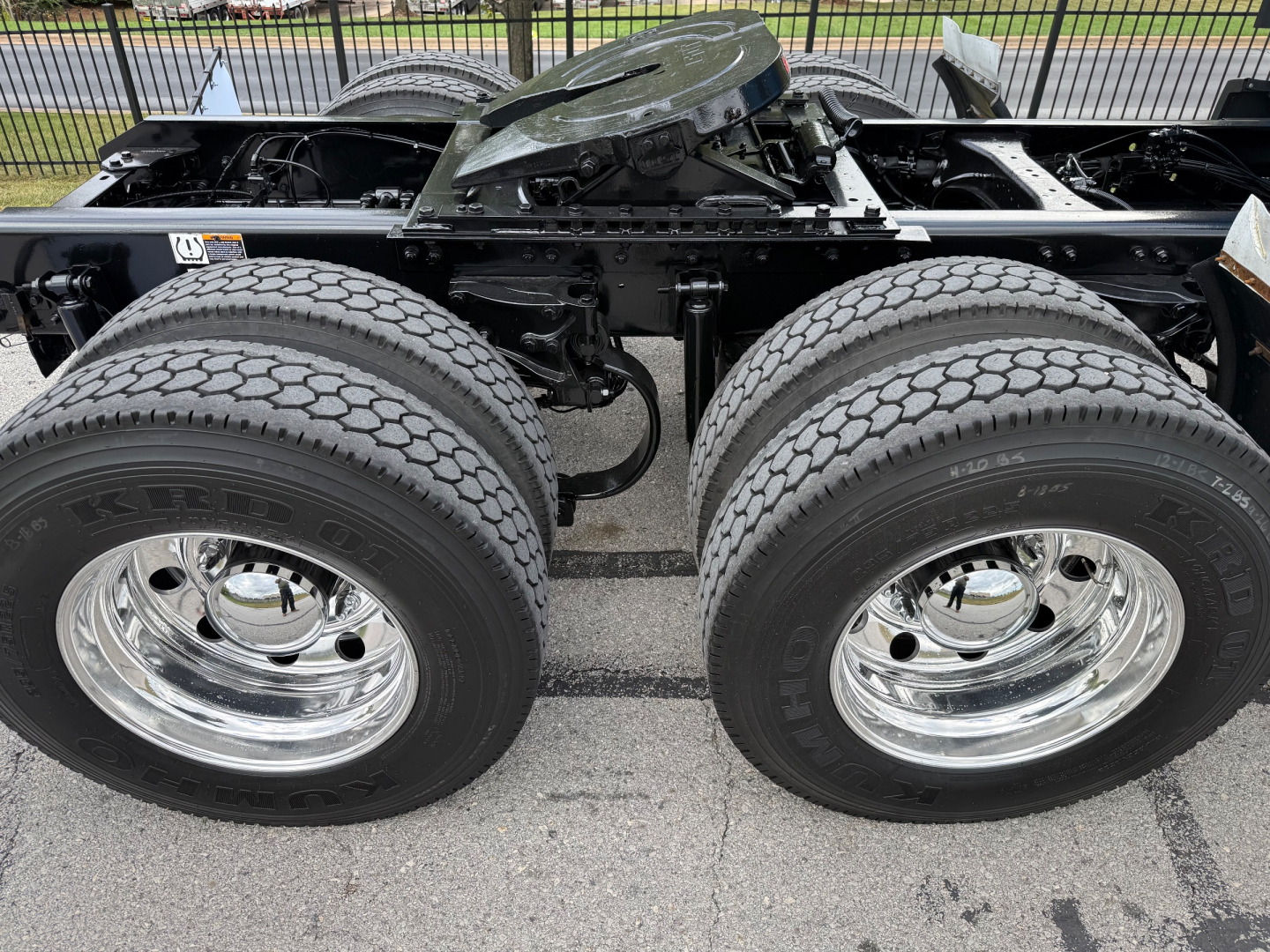 Kenworth T680 chassis showing dual rear wheels and suspension components with chrome rims and tires.