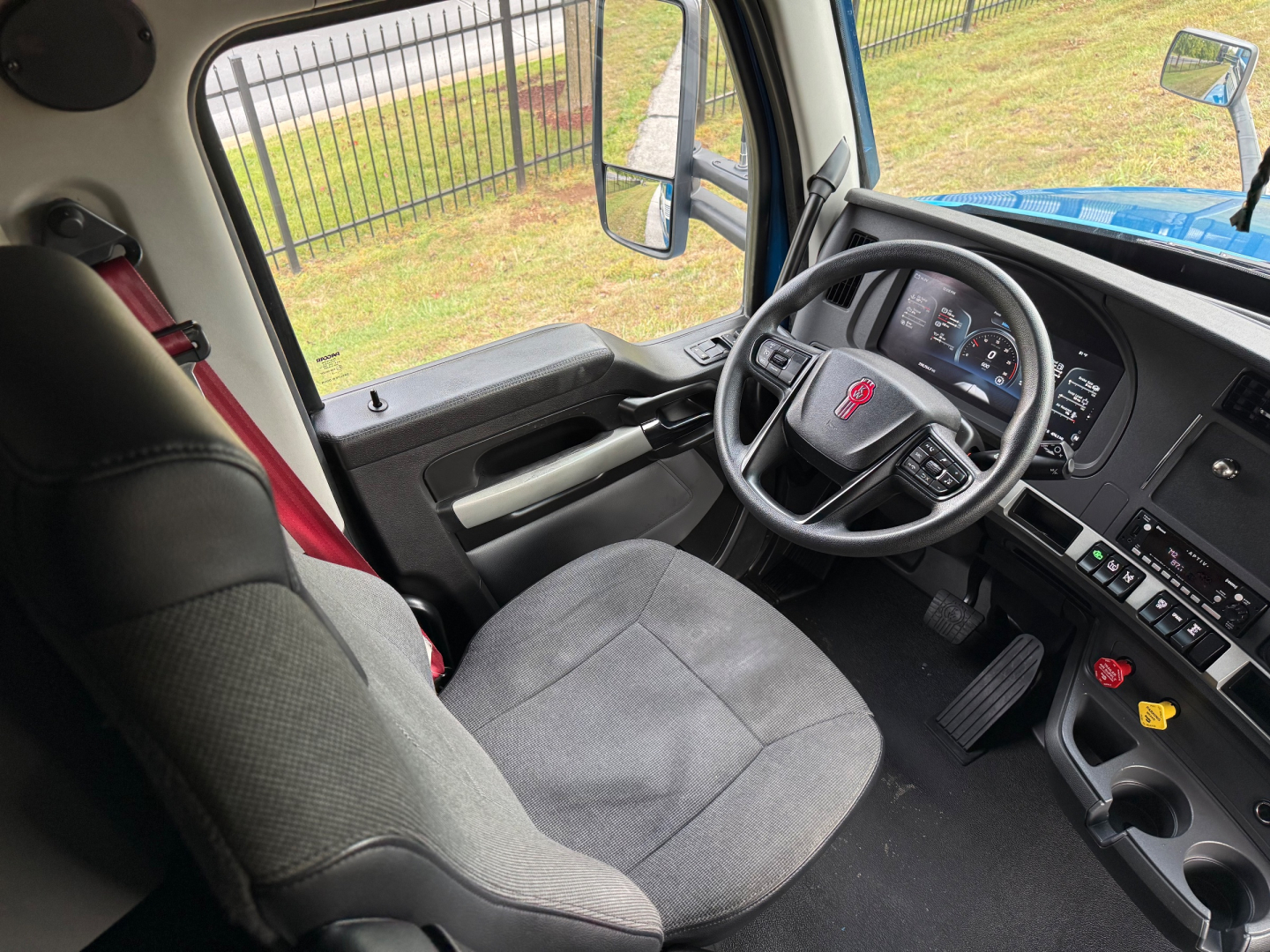 Kenworth T680 truck interior cockpit view showing steering wheel, dashboard, and driver seat from the passenger side.