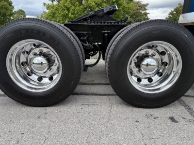 Kenworth T680 wheel pair showing dual rear axles and chrome hubcaps with tire tread details.