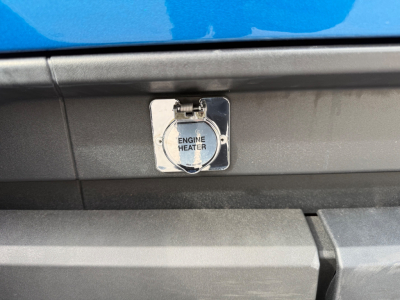 Kenworth T680 engine heater fuel cap area showing chrome filler cap labeled Engine Heater on black panel under blue body panel.