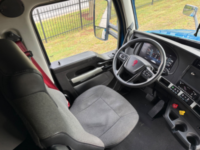Kenworth T680 truck interior cockpit view showing steering wheel, dashboard, and driver seat from the passenger side.