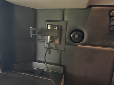 Kenworth T680 interior storage with a small mounted panel and circular power outlet, showing a loose cable and interior paneling.