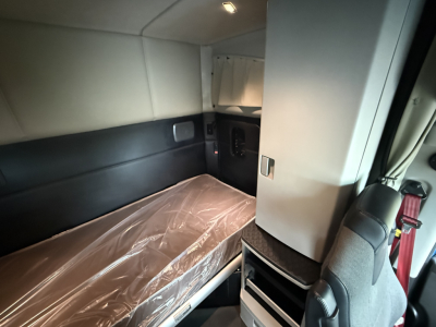 Kenworth T680 sleeper cab interior showing bunk bed with plastic cover and storage cabinet.