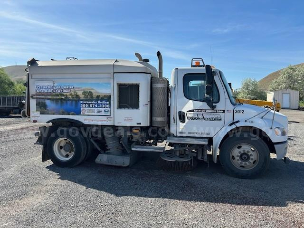 Freightliner M2 106 sweeper truck side view showing rear hopper and cab details.