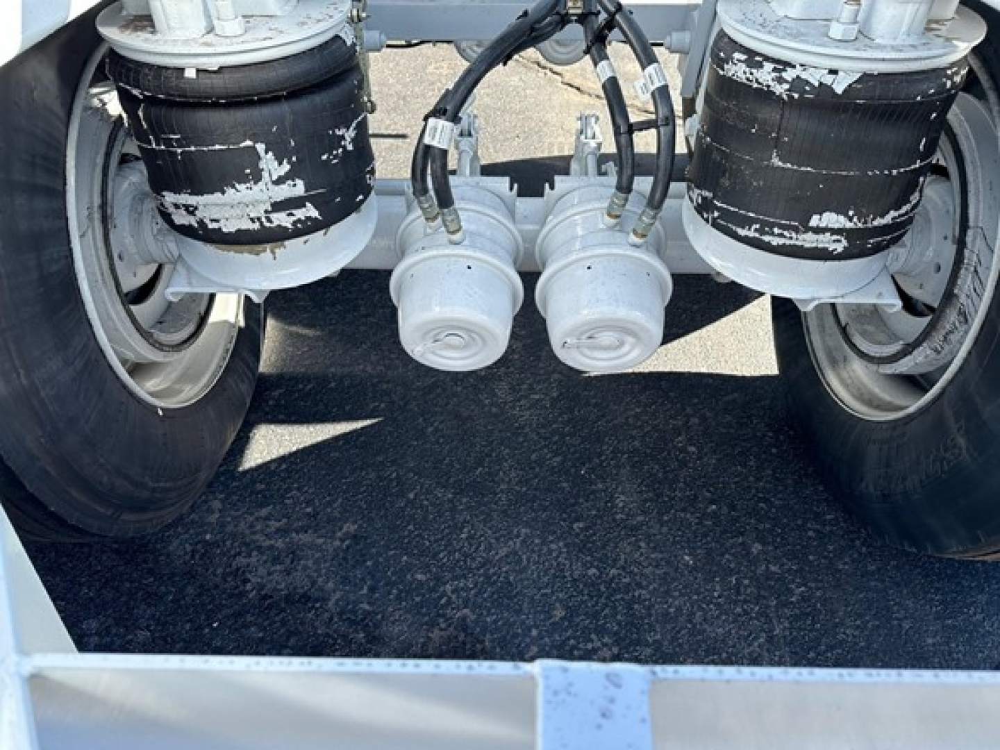 Bottom dump trailer air ride undercarriage showing air suspension bags and hoses between rear axles.