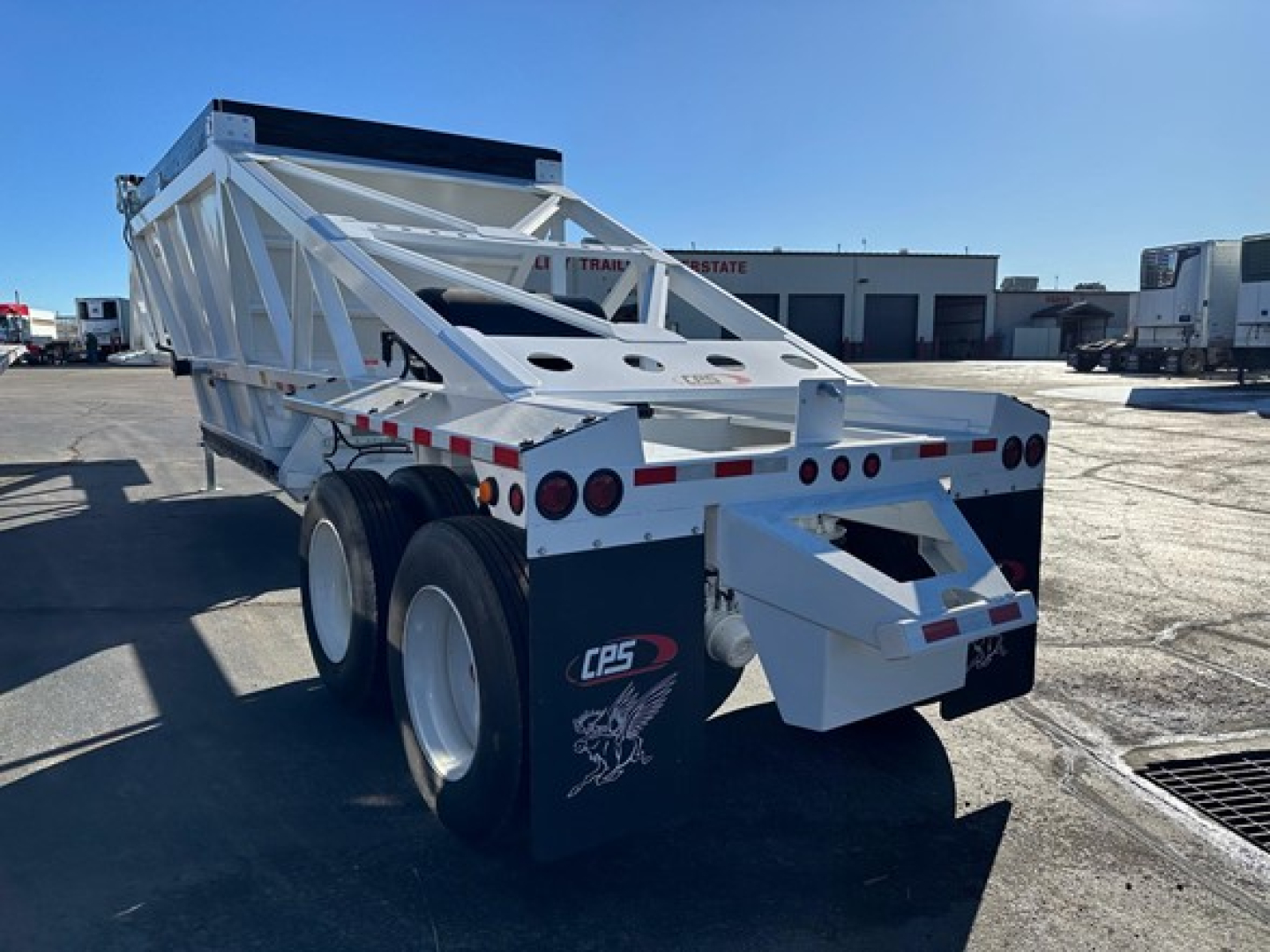 CPS air ride bottom dump trailer showing white frame, dual rear axles, and rear ramp with CPS logo and safety lights.