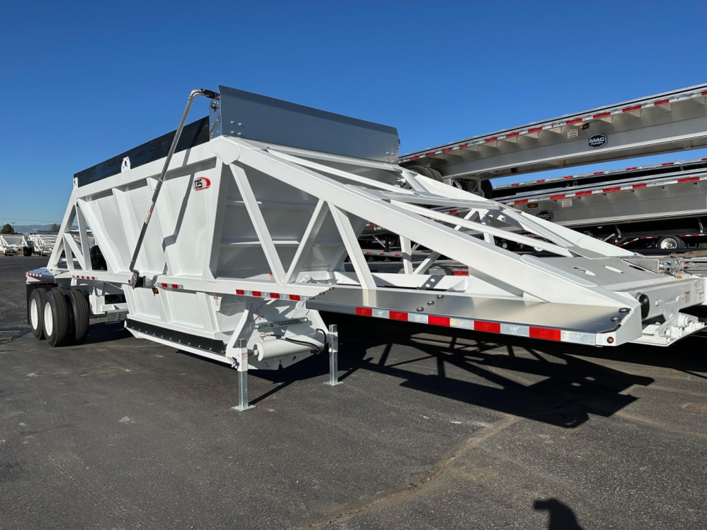 Dump trailer with white air-ride bottom-dump structure, support legs down, rear discharge chute, and long triangular truss framing in an outdoor lot.