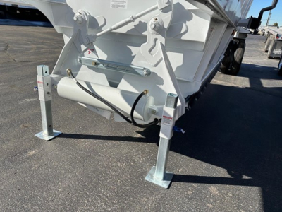 Bottom dump trailer showing undercarriage with hydraulic cylinder and support stands.