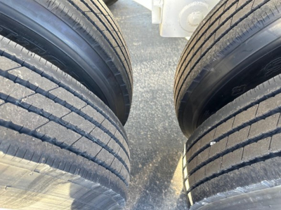 Trailer tires close-up showing dual wheels and tread on a bottom-dump trailer chassis.