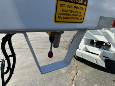 Trailer undercarriage showing a yellow warning label and a red-tipped hitch/valve on a CPS air ride bottom dump trailer.
