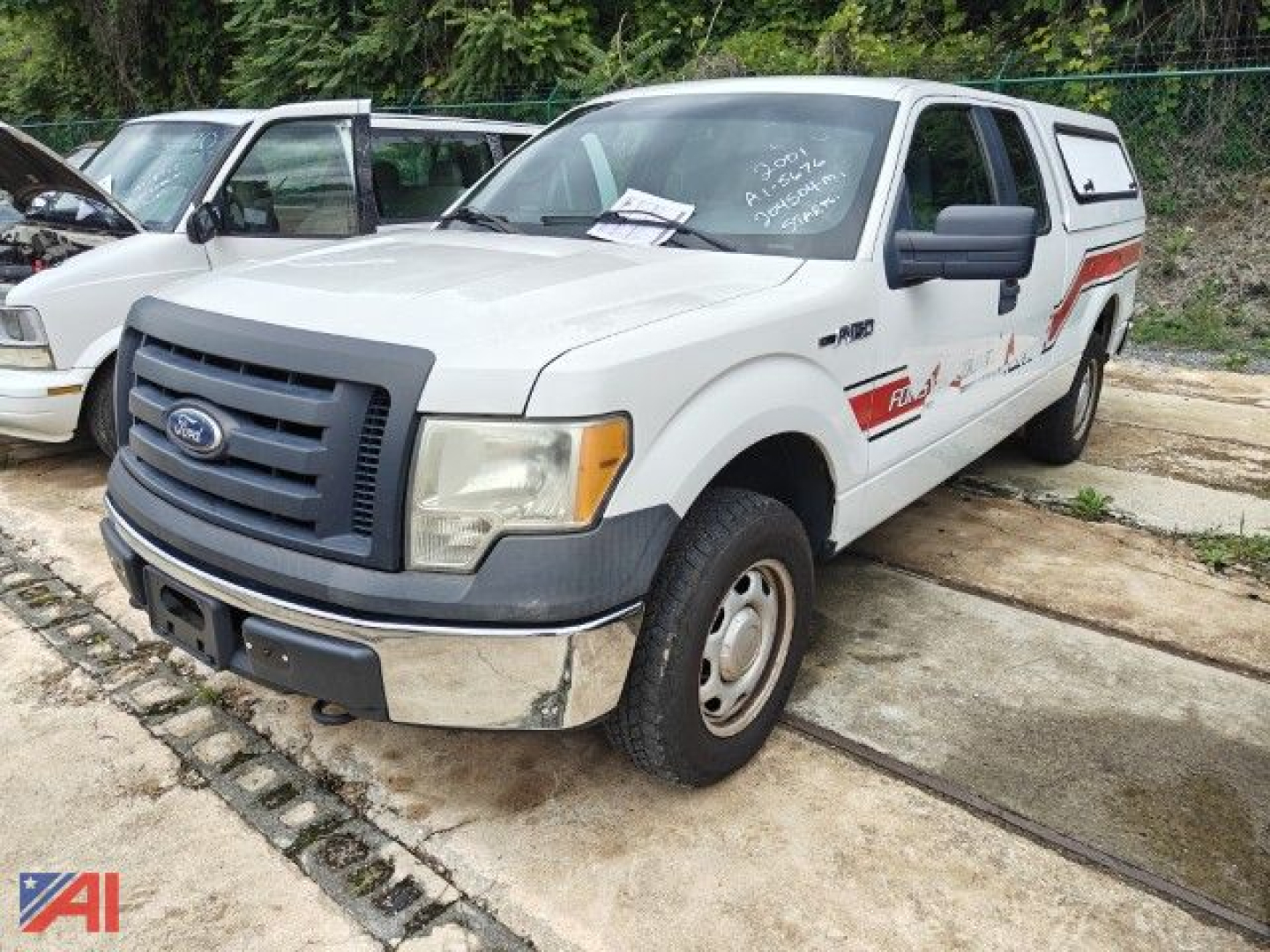 Ford F-150 crew cab emergency truck with cap, front-left view, gray body with black grille and bumper, emergency decals along side.